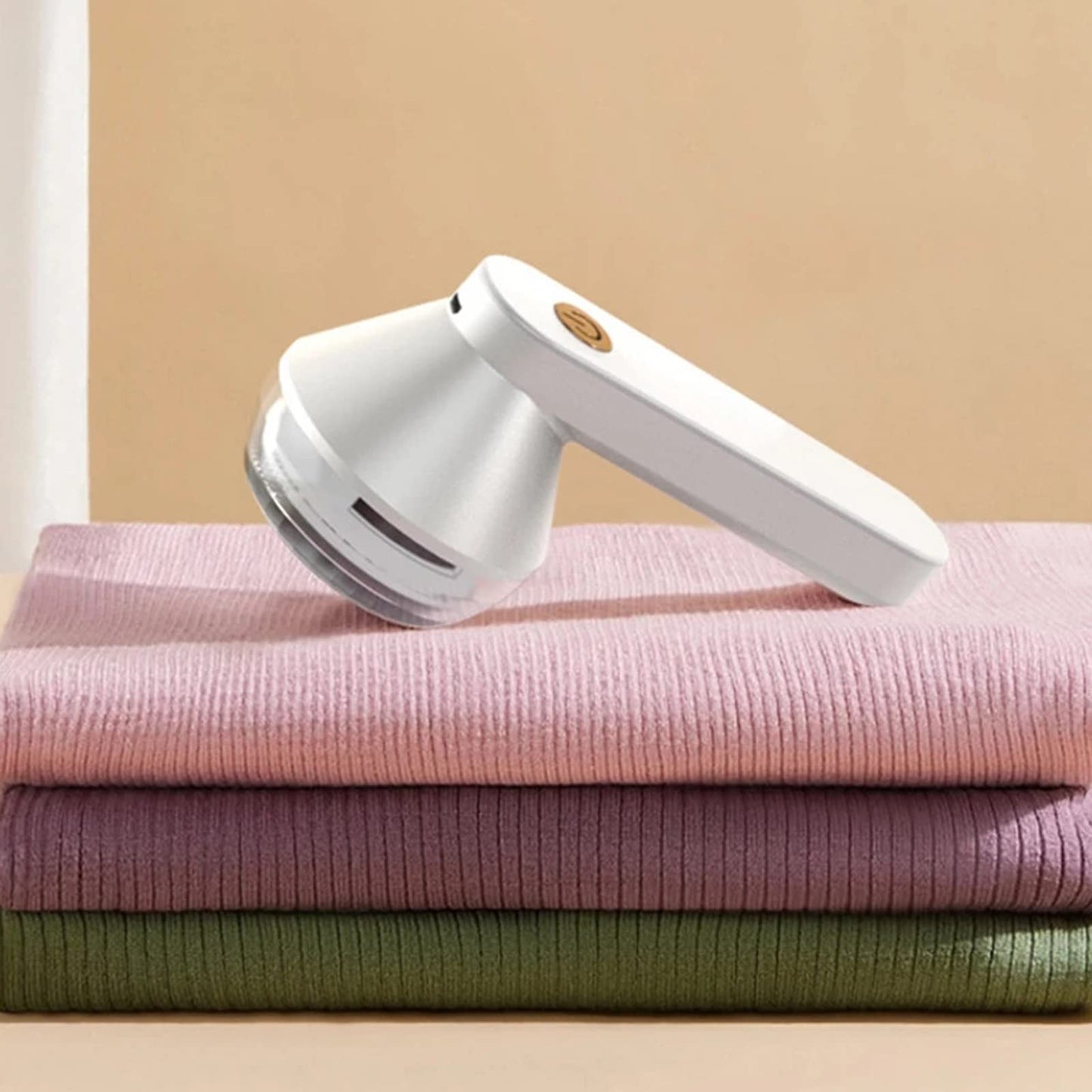 Rechargeable lint remover on folded knit sweaters, white and silver device